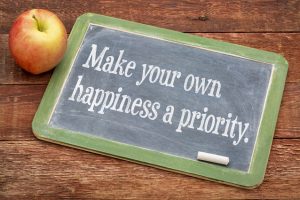 Make your own happiness priority - advice on a slate blackboard against red barn wood