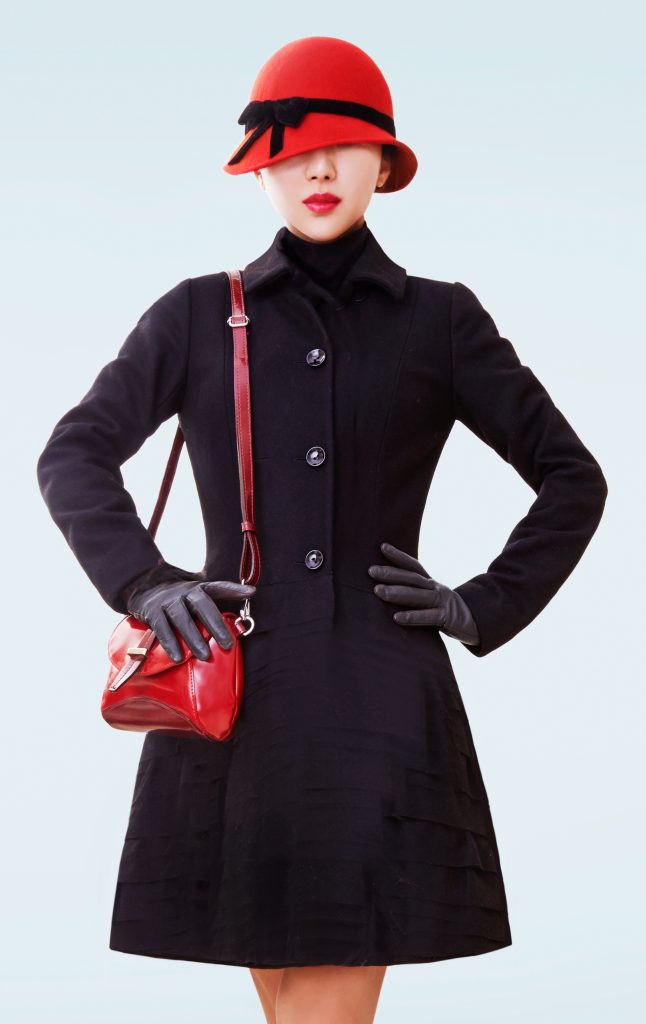 Winter Fashion look woman. Black coat, hat and handbag.isolated on light blue background.